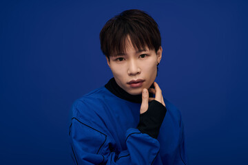 Young handsome Asian man posing thoughtfully against a vibrant blue backdrop