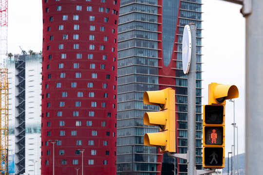 Close-up of traffic signals in a cityscape, featuring red and yellow lights contrasting with skyscrapers.