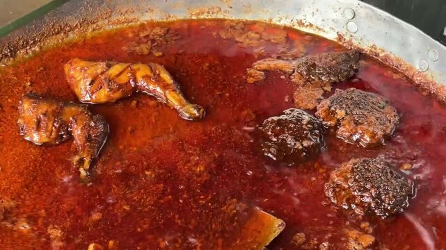 A big hot vessel containing oily, spicy mutton and chicken chap.