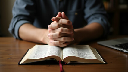 Young Man Praying with Clasped Hands and Bible on Wooden Desk - Faith, Prayer, and Devotion Concept