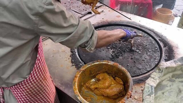 Close up shot of a man putting chicken kabab in a skewer in a tandoor
