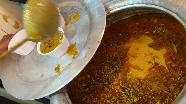 A man putting mutton Halim in a plastic container in India during Ramzan