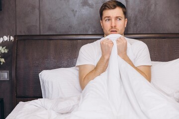 Scared Man Hiding Under Blanket in Bed After Nightmare