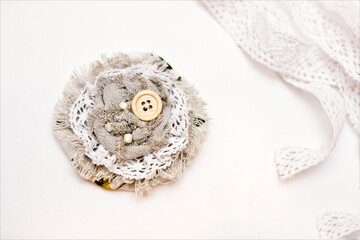 Handmade boho brooch made of linen fabric, cotton lace and wooden buttons. Handmade designer accessory on a white background close-up.
