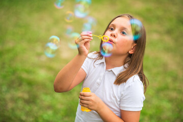 Girl blowing soap bubbles outdoors in a sunny summer day