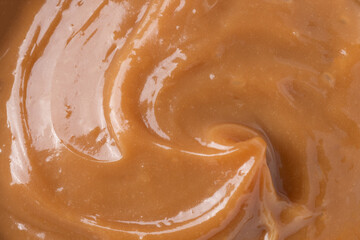 Detail of doce de leite or dulce de leche, traditional brazilian creamy milk sweet over wooden table
