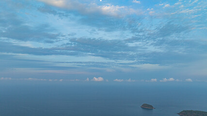 Aerial view A breathtaking view of a coastal city at sunset, with golden hues illuminating the sky and reflecting on the calm ocean. Small islands and boats are visible in the distance.