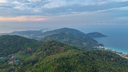 Aerial view A breathtaking view of a coastal city at sunset, with golden hues illuminating the sky and reflecting on the calm ocean. Small islands and boats are visible in the distance.