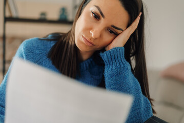 Stressed woman reading bad news in a letter at home