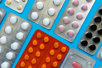 pharmacy colorful medicament pills and tablets in blisters on blue background