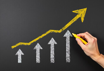 Hand drawing upward trend arrow graph on blackboard. Growth, success, business concept.
