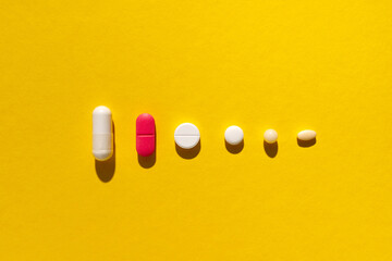 pharmacy colorful medicament pills and capsules on yellow background