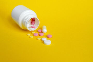 pharmacy colorful medicament pills and capsules with bottle on yellow background