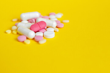 pharmacy colorful medicament pills and capsules on yellow background