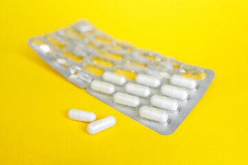 pharmacy medicament white capsules in blister on yellow background