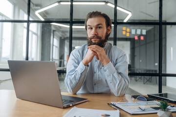 Obraz premium Front view, by laptop. Businessman is working in the office