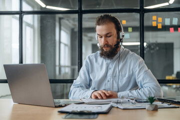 Obraz premium Sitting in headphones, online conference. Businessman is working in the office