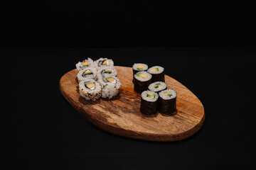 Wooden Platter With Assorted Sushi Rolls on Dark Background