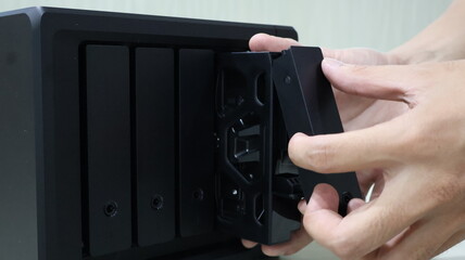 close up of someone's hand inserting a hard disk into a Network Attached Storage