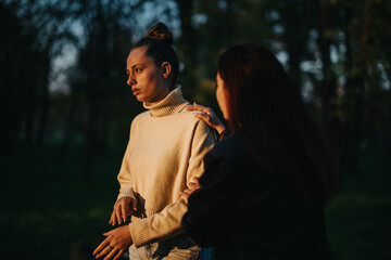 A heartfelt moment between two people, captured in warm tones amidst a lush forest background....
