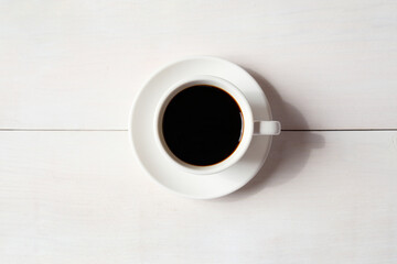 A cup of coffee on white wooden background..