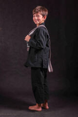 laughing boy in a black kimono with a gray belt draped over his shoulder