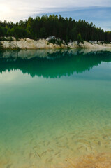 Summer landscape view of forest trees and transparent emerald waters of kaolin quarry locally named...