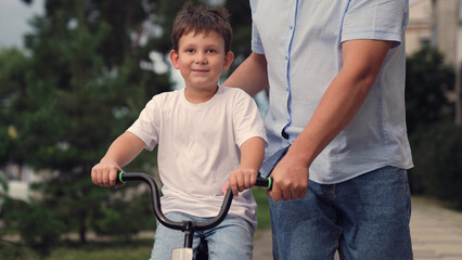 father teaches child ride bike, boy laughs smiling sitting bike outdoors, horse riding, boy laugh...