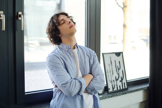 Confident young man exudes charm in modern office setting amidst natural light