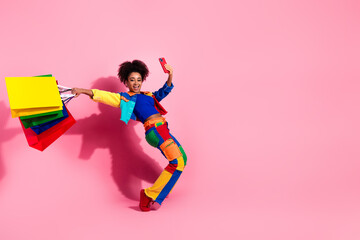 Joyful woman holding colorful shopping bags taking selfie on pink background