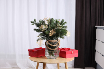 Beautiful composition of decorated fir tree branches and Christmas gifts on table indoors