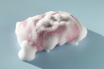 Soap bar with foam on grayish blue background, closeup