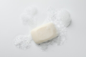 Soap bar with foam on white background, top view