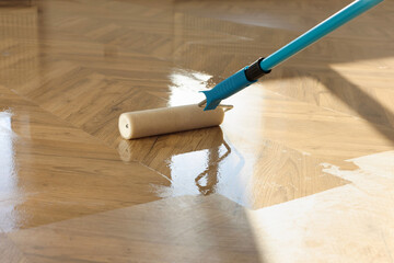 Polishing parquet with roller and varnish indoors, closeup