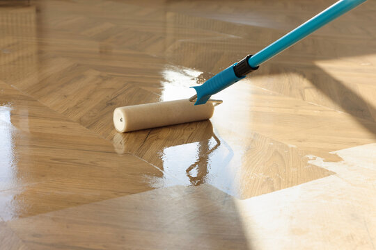 Polishing parquet with roller and varnish indoors, closeup