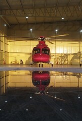 red helicopter inside the hangar with reflection on water at the ground  © Jordan