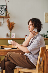 Young handsome man enjoying a coffee break in a warm office environment while working