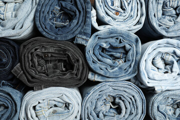 Different stylish rolled jeans as background, top view