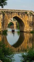 Fototapeta premium Tourists enjoy a boat ride under historic arches reflecting in calm waters