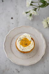 Lemon Poppy Seed Cupcakes with lemon curd and cream cheese topping. Cupcake in form of Fried Egg. Colourful Easter eggs, flowers on a stone background, top view. Easter holiday and festive food.