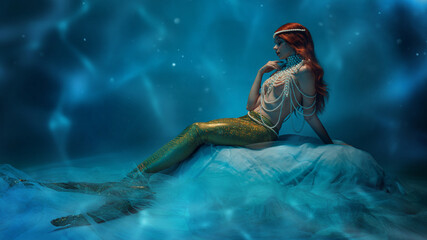 Mysterious beauty. Redhaired attractive woman with mermaid tail and pearl top tenderly sitting deep...