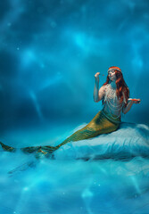 Mysterious young, mermaid queen with long red hair and sparkling pearls sitting and eating red...