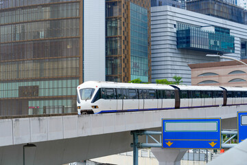 High-speed, driverless metro train travels across a city skyline on a bridge interchange against the backdrop of buildings
