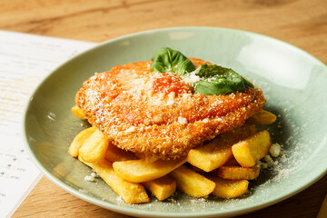 Crispy Chicken Schnitzel with Fries and Basil Garnish