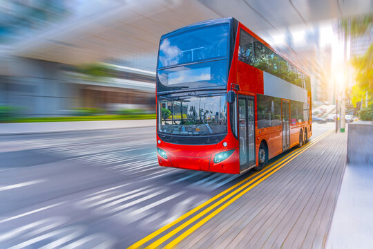 Colorful red double-decker bus moves quickly through motion blur effect busy speed city area surrounded by modern buildings