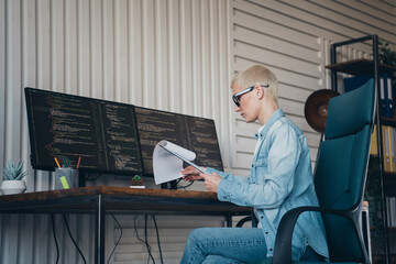 Professional young woman coding at dual monitors in a modern office