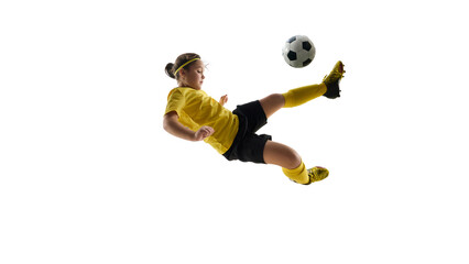 Dynamic image of girl, soccer player in yellow jersey and black shirt during game, training, kicking ball in jump and falling down against white background. Concept of sport, childhood, competition,