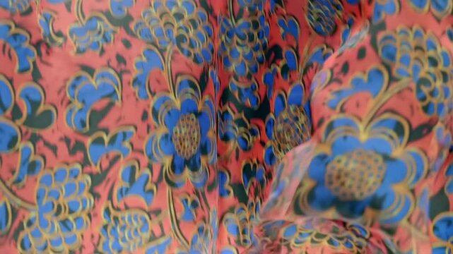 Red fabric with beautiful blue floral pattern falls, fluttering on a black background. Closeup. Macro. Slow mo, slow motion, high speed camera, 200fps