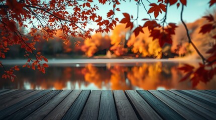 An autumn scene with vibrant orange and red leaves on tree branches framing a calm lake, a rustic wooden deck or table in the foreground, and blurred autumn foliage reflecting in the water