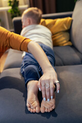 Mother holding son's feet while relaxing on sofa at home